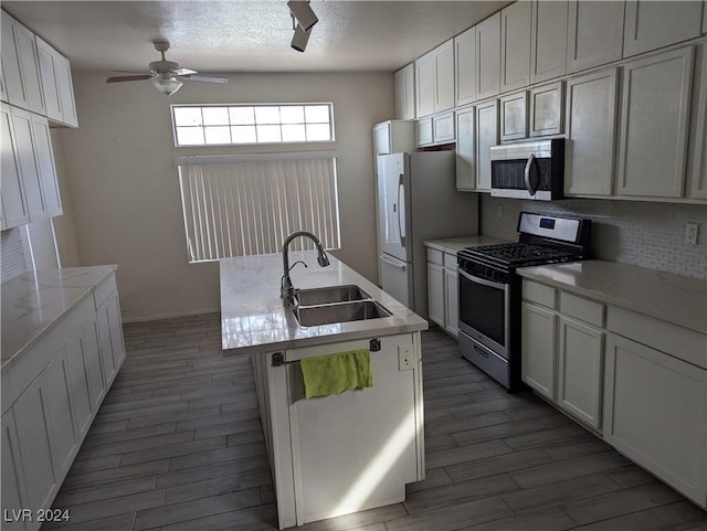 kitchen with appliances with stainless steel finishes, a center island with sink, white cabinetry, and sink