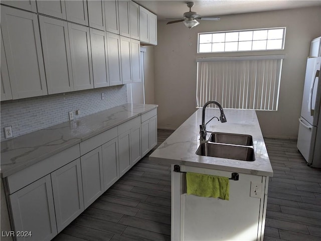 kitchen with a kitchen island with sink, sink, white refrigerator, white cabinets, and dark hardwood / wood-style floors