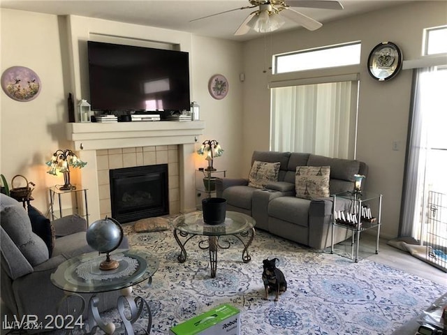 living room featuring ceiling fan and a tiled fireplace