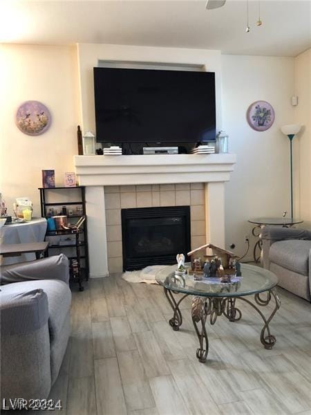 living room featuring a tile fireplace, hardwood / wood-style floors, and ceiling fan