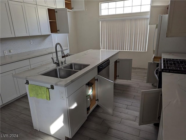 kitchen featuring tasteful backsplash, light stone counters, sink, white cabinets, and hardwood / wood-style floors