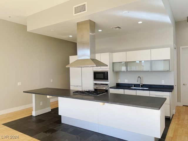 kitchen featuring sink, island exhaust hood, white cabinetry, and stainless steel appliances