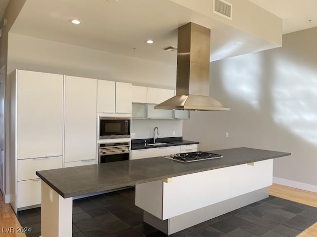 kitchen with a kitchen breakfast bar, island range hood, white cabinetry, and stainless steel appliances