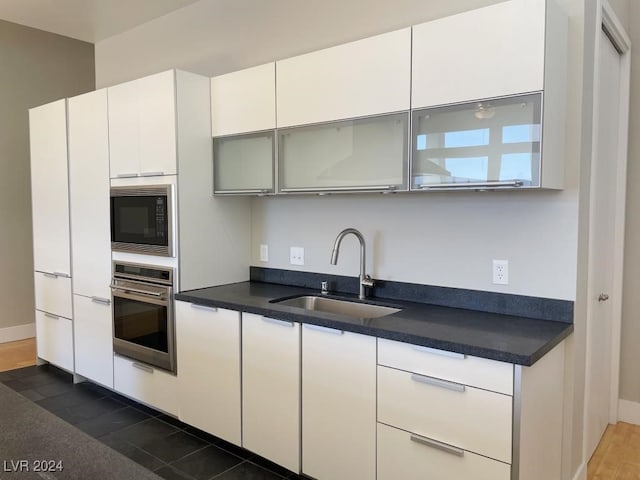 kitchen with dark wood-type flooring, white cabinets, oven, sink, and black microwave