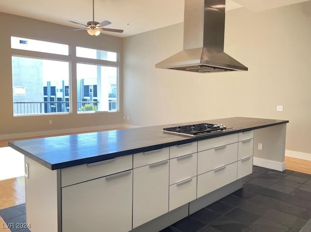 kitchen with stainless steel gas stovetop, a center island, ventilation hood, white cabinets, and ceiling fan