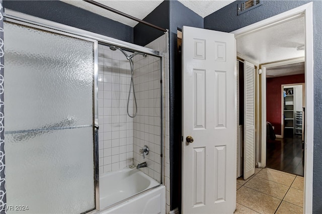 bathroom featuring a textured ceiling, tile patterned floors, and enclosed tub / shower combo