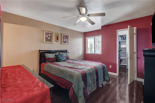 bedroom featuring a textured ceiling, ceiling fan, a spacious closet, and dark wood-type flooring