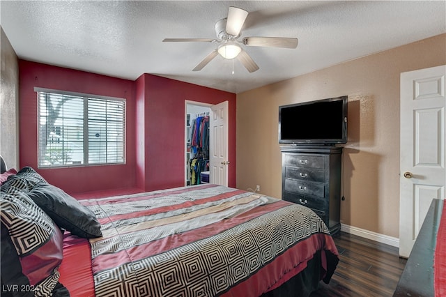 bedroom with a textured ceiling, ceiling fan, a spacious closet, dark hardwood / wood-style floors, and a closet