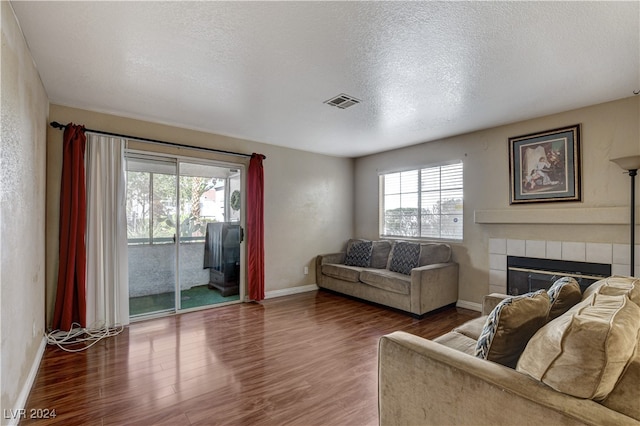 living room with a fireplace, hardwood / wood-style floors, a textured ceiling, and plenty of natural light