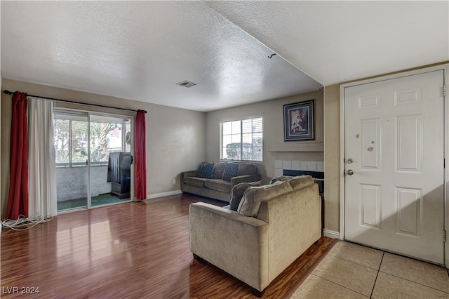 living room with hardwood / wood-style floors, a fireplace, and a textured ceiling