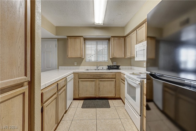 kitchen with light brown cabinetry, white appliances, sink, tile countertops, and light tile patterned flooring