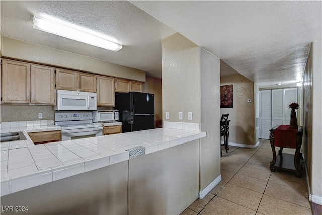 kitchen featuring tile countertops, light brown cabinets, white appliances, a textured ceiling, and light tile patterned flooring