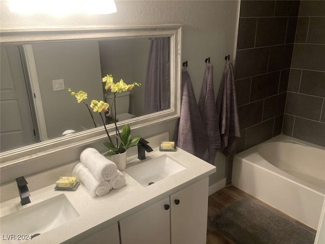 bathroom with vanity, wood-type flooring, and tiled shower / bath