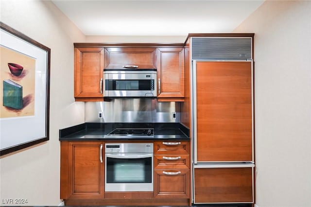 145 Harmon Ave Unit 208, Las Vegas, NV 89109 - kitchen with appliances with stainless steel finishes, dark countertops, brown cabinets, and baseboards