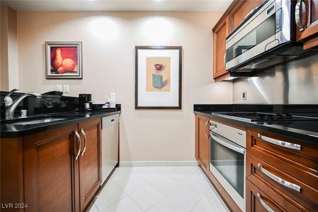 145 Harmon Ave Unit 208, Las Vegas, NV 89109 - kitchen featuring stainless steel appliances, a sink, dark countertops, brown cabinets, and baseboards