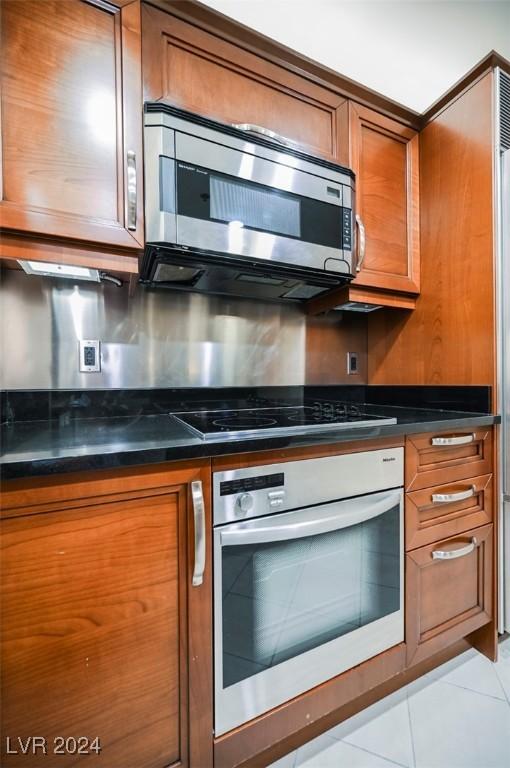 145 Harmon Ave Unit 208, Las Vegas, NV 89109 - kitchen featuring wall oven, stainless steel microwave, brown cabinets, dark countertops, and black electric stovetop
