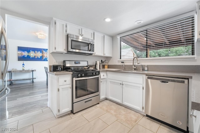 kitchen with white cabinetry, sink, light hardwood / wood-style floors, and appliances with stainless steel finishes