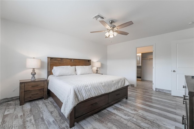 bedroom featuring light wood-type flooring, a spacious closet, a closet, and ceiling fan