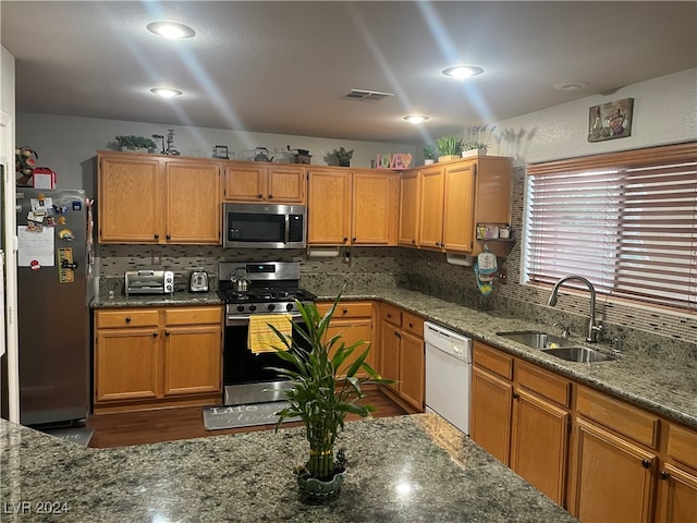 kitchen featuring stainless steel appliances, tasteful backsplash, stone countertops, dark hardwood / wood-style flooring, and sink