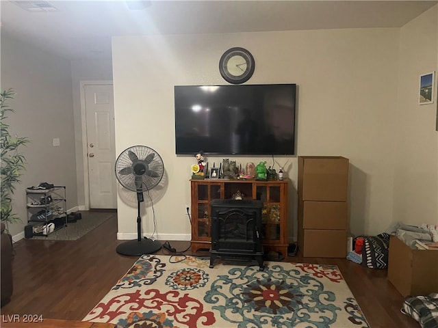 living room featuring dark wood-type flooring and a wood stove