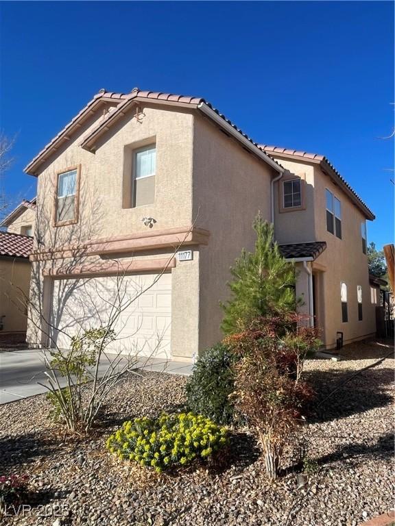 view of side of property featuring driveway, a garage, and stucco siding