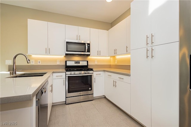 kitchen with stainless steel appliances, light countertops, white cabinetry, and a sink