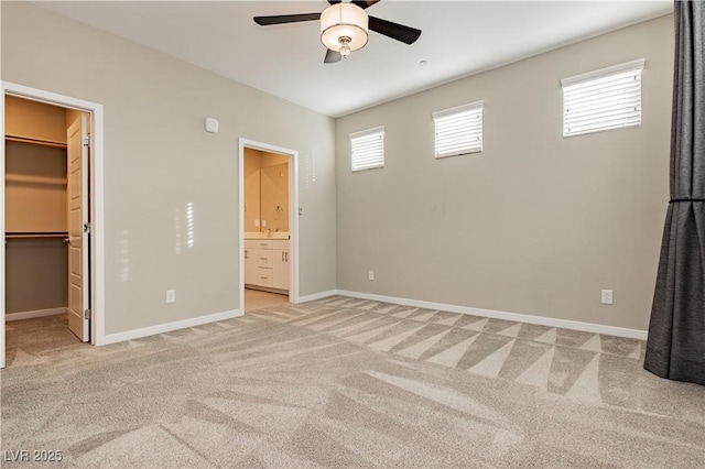 unfurnished bedroom with a walk in closet, ceiling fan, connected bathroom, light colored carpet, and a closet