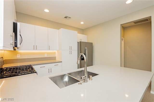 kitchen with white cabinetry, stainless steel fridge, stove, and sink