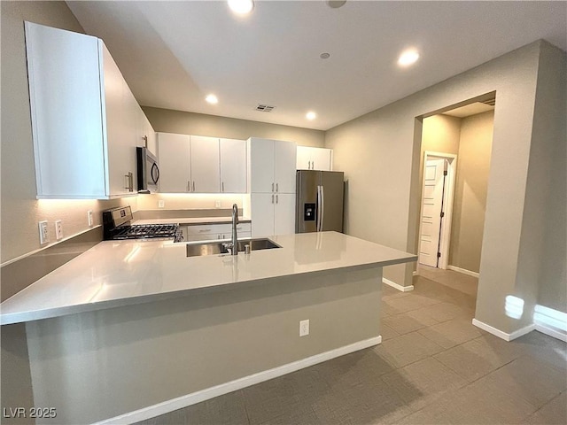 kitchen with white cabinets, kitchen peninsula, sink, and appliances with stainless steel finishes