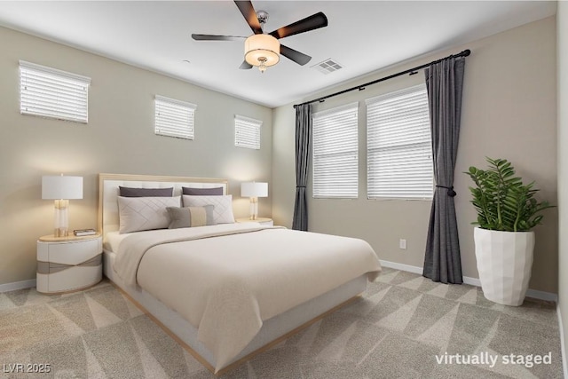 carpeted bedroom with a ceiling fan, visible vents, baseboards, and multiple windows