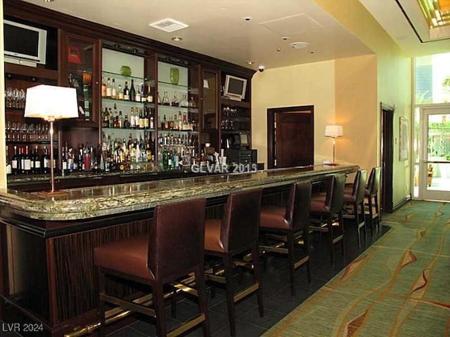 bar with dark brown cabinets, dark stone countertops, and dark tile patterned floors