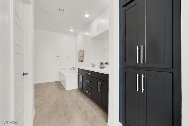 bathroom with a tub, tile patterned flooring, and vanity