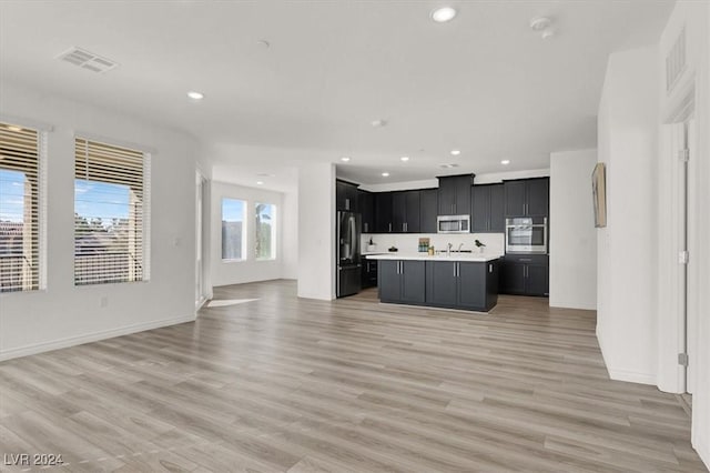 kitchen featuring an island with sink, light hardwood / wood-style floors, and appliances with stainless steel finishes