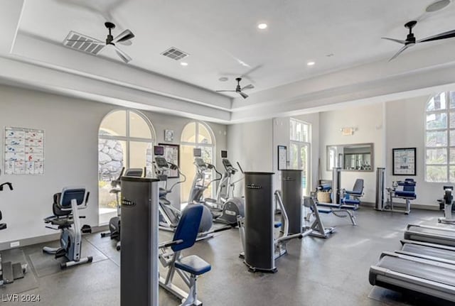 workout area with a raised ceiling and ceiling fan