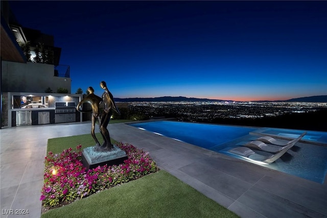 pool at dusk with area for grilling and a mountain view