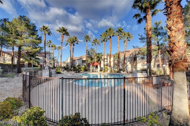 pool with a patio, fence, and a residential view