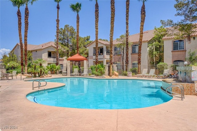 community pool featuring a residential view, fence, and a patio