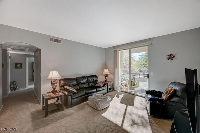 living room featuring arched walkways, carpet flooring, and visible vents