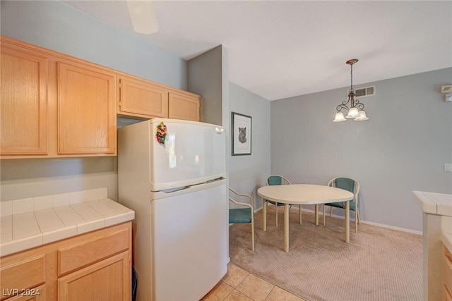 kitchen featuring a notable chandelier, tile countertops, visible vents, light brown cabinetry, and freestanding refrigerator