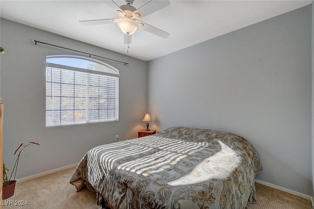 carpeted bedroom with ceiling fan and baseboards