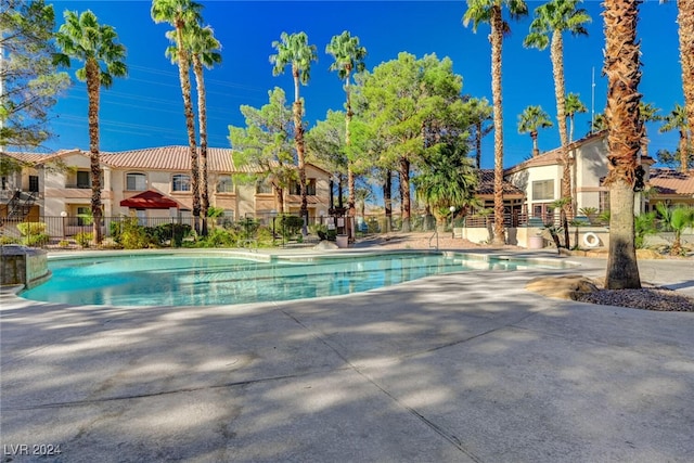 community pool with a patio area, a residential view, and fence