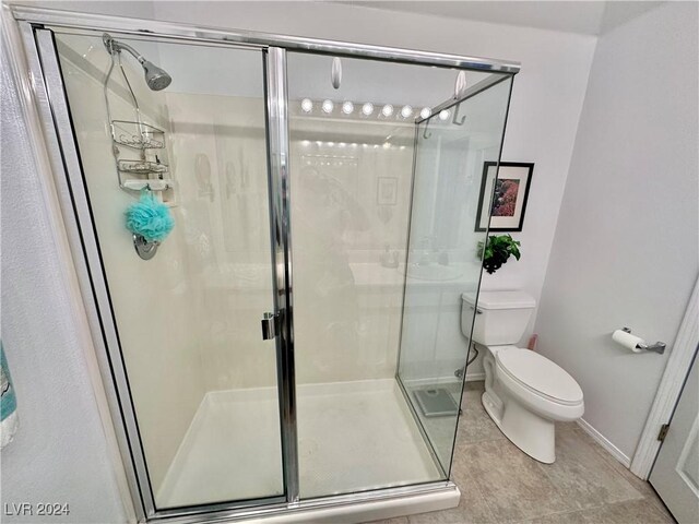 bathroom with toilet, tile patterned floors, and a shower with shower door