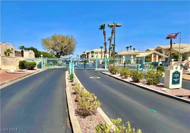 view of road featuring a gated entry, a residential view, a gate, and curbs