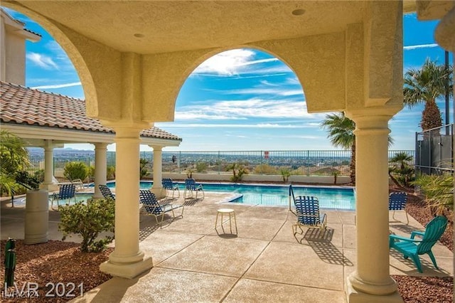 community pool with a patio area and fence