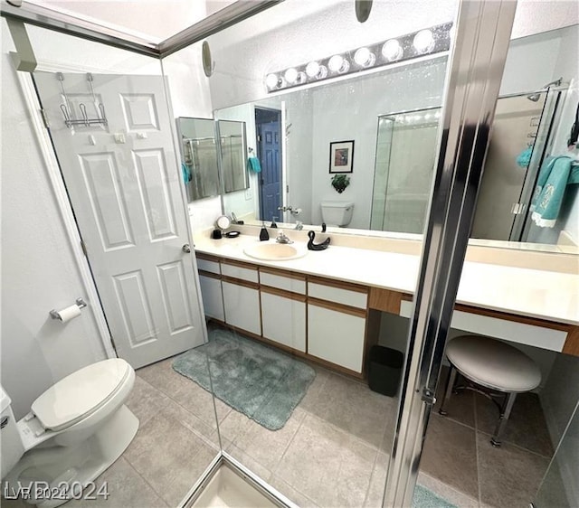 bathroom featuring walk in shower, vanity, toilet, and tile patterned flooring