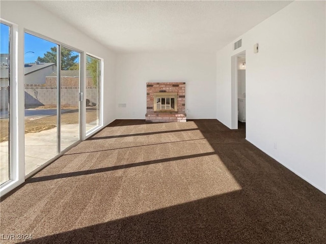 unfurnished living room featuring a fireplace and dark colored carpet