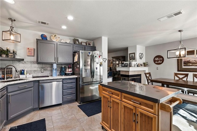 kitchen with decorative backsplash, appliances with stainless steel finishes, sink, gray cabinets, and hanging light fixtures