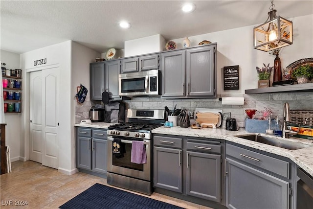 kitchen featuring appliances with stainless steel finishes, gray cabinets, hanging light fixtures, and sink