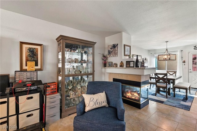 sitting room with a multi sided fireplace, a textured ceiling, and a notable chandelier