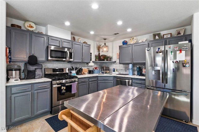 kitchen with sink, hanging light fixtures, decorative backsplash, a textured ceiling, and appliances with stainless steel finishes